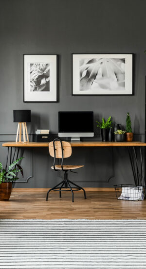 Real photo of open space apartment interior with beige sofa next to the window and desktop computer o a wooden desk