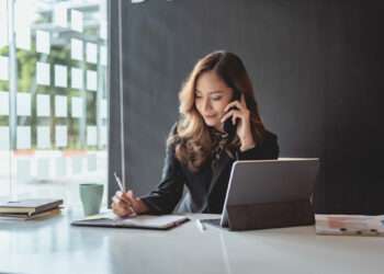 Young asian businesswoman beautiful charming smiling and talking on the mobile phone in the office.